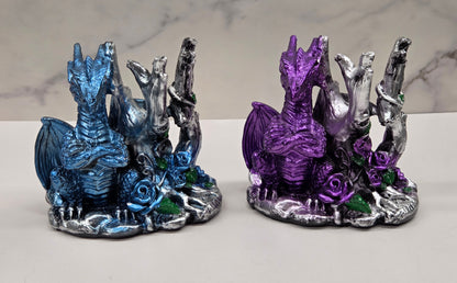 Plastic dragon shaped sphere holders in blue and purple against a white background
