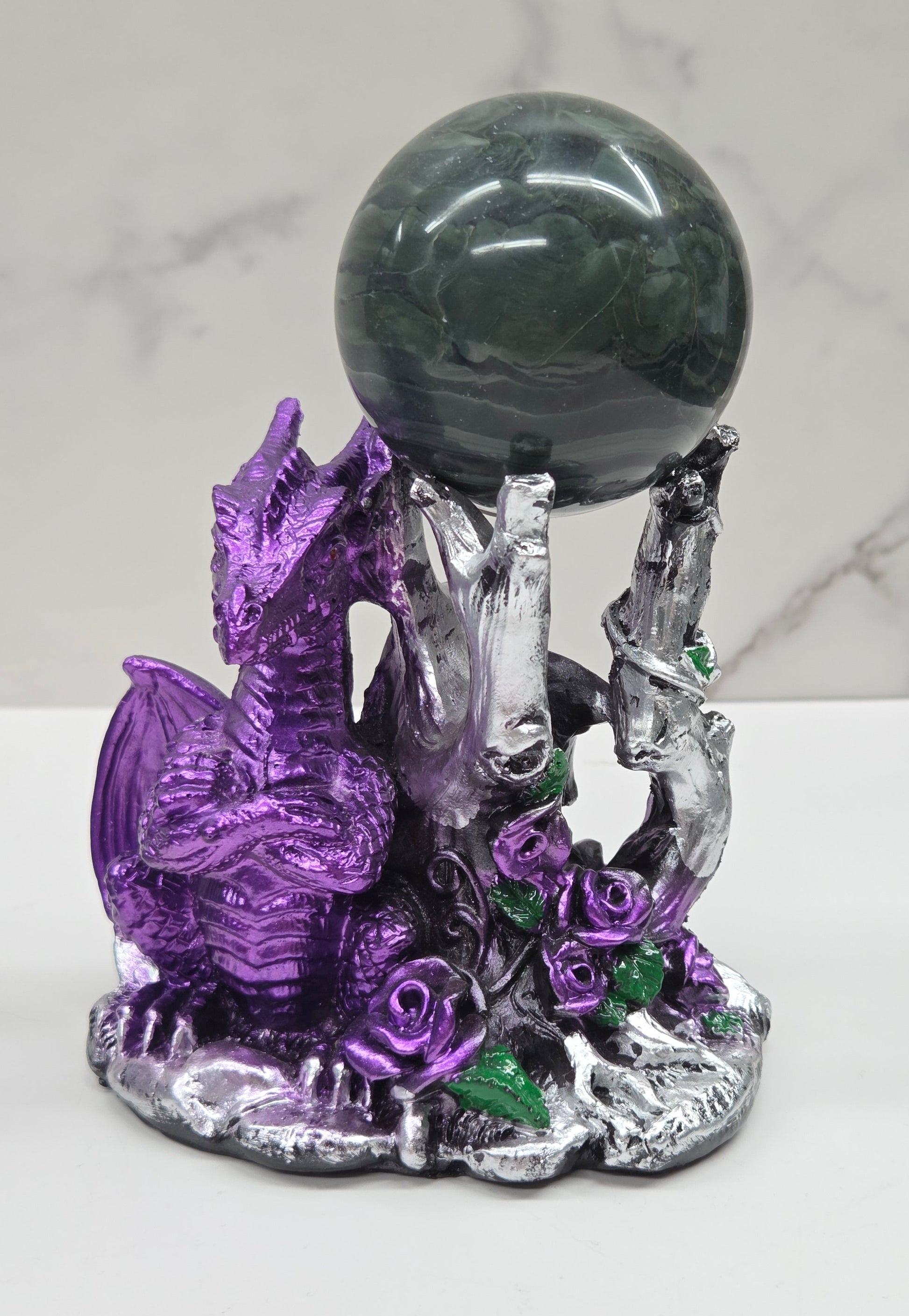 Plastic dragon shaped sphere holders in purple holding a sphere against a white background