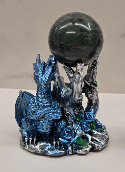 Plastic dragon shaped sphere holders in blue holding a sphere against a white background