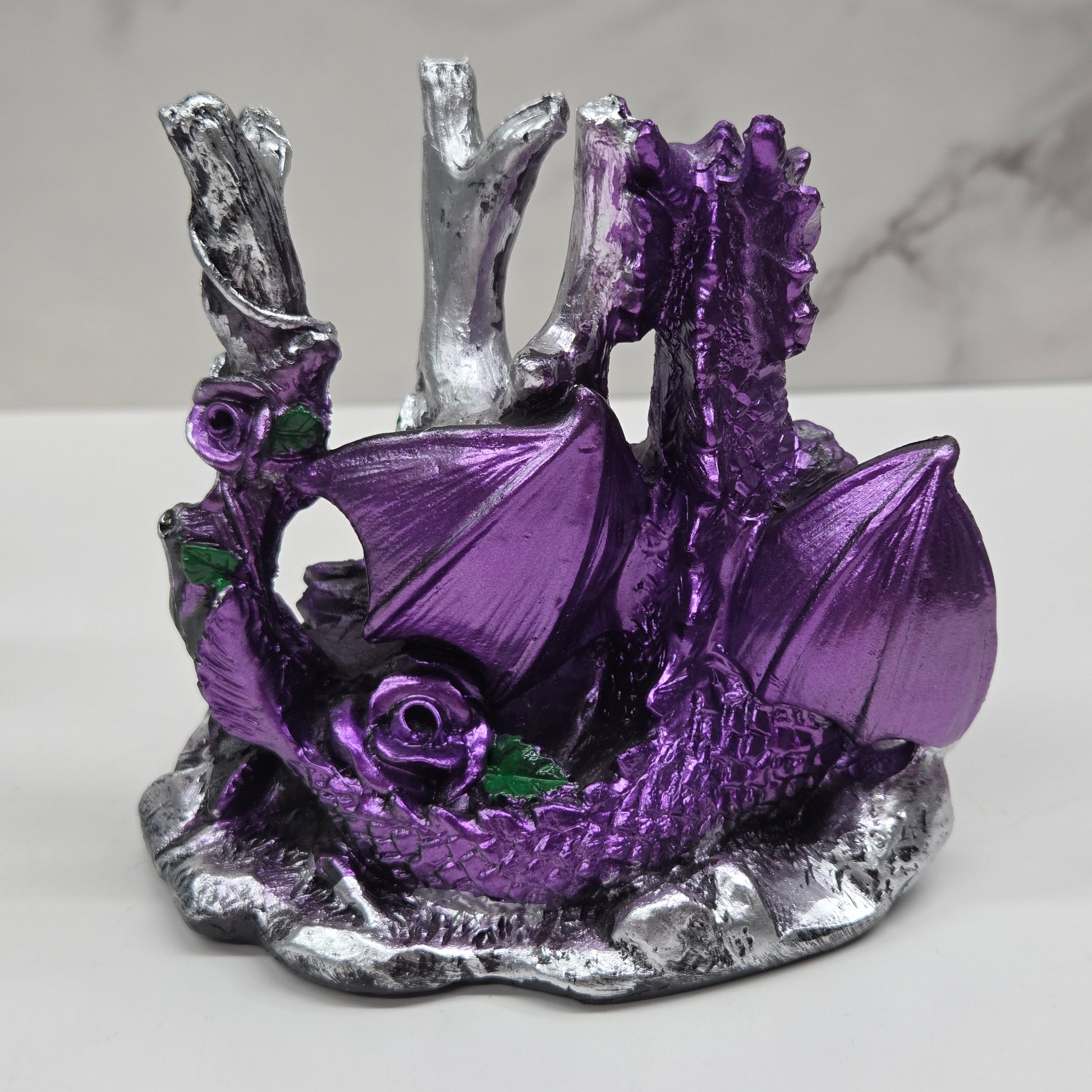 Plastic dragon shaped sphere holders in purple holding a sphere against a white background