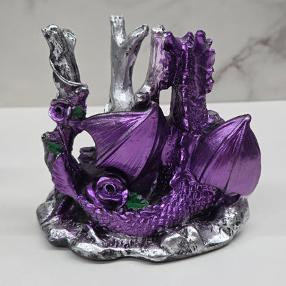 Plastic dragon shaped sphere holders in purple holding a sphere against a white background