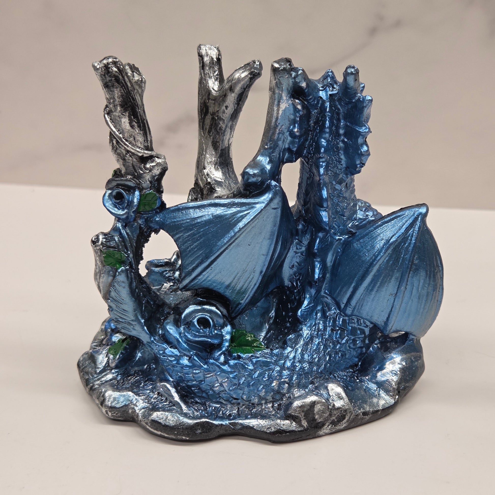 Plastic dragon shaped sphere holders in blue holding a sphere against a white background