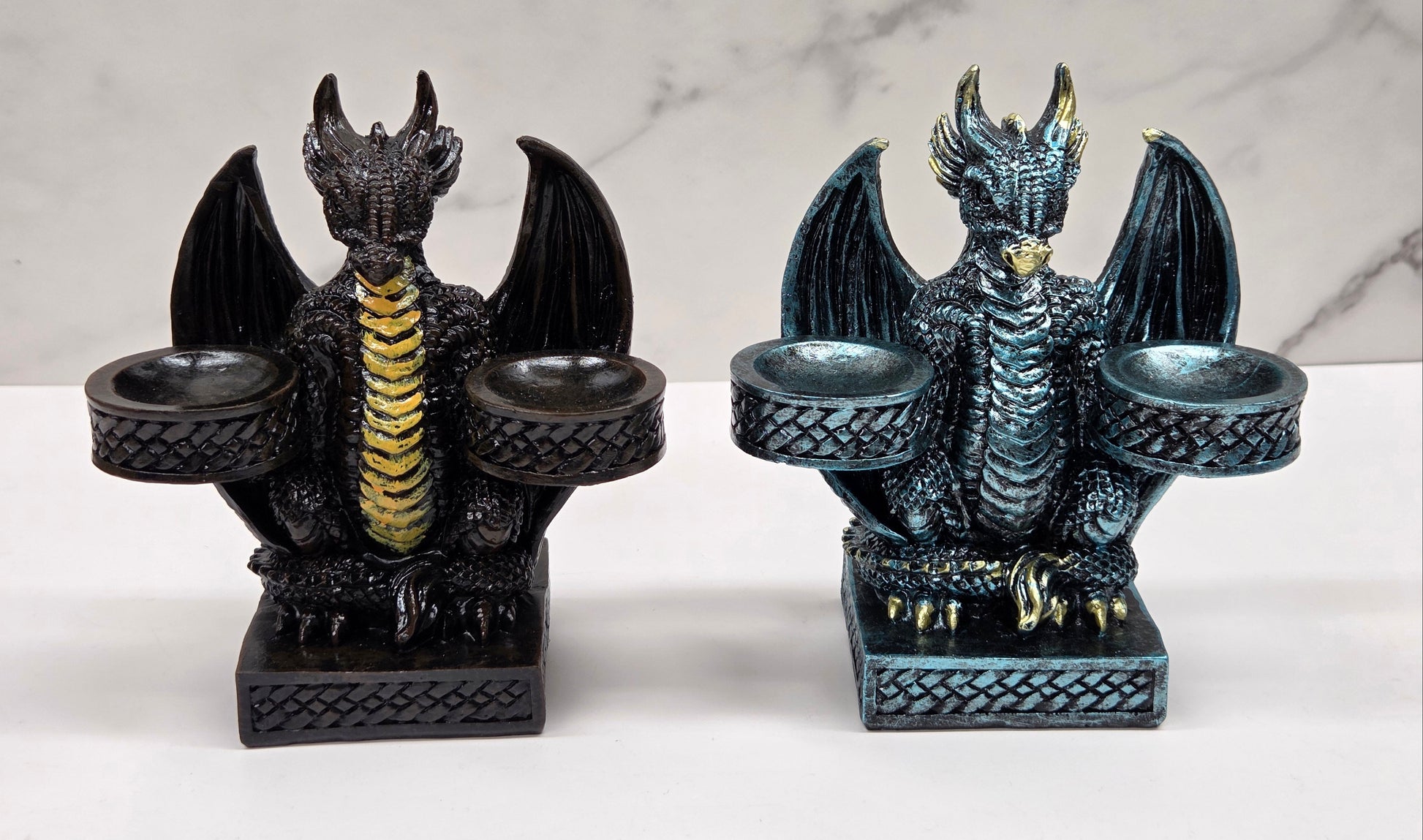 Two dragon-shaped sphere holders on a white surface with a marble background