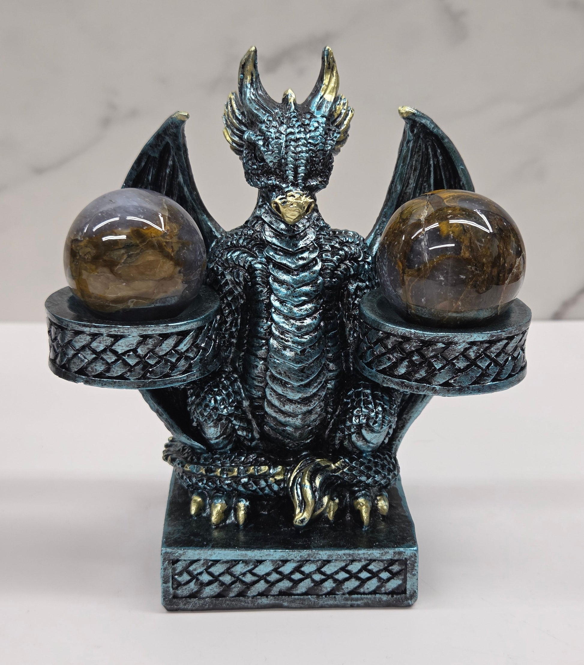 Decorative dragon-shaped sphere holder with 2 small spheres on a marble surface