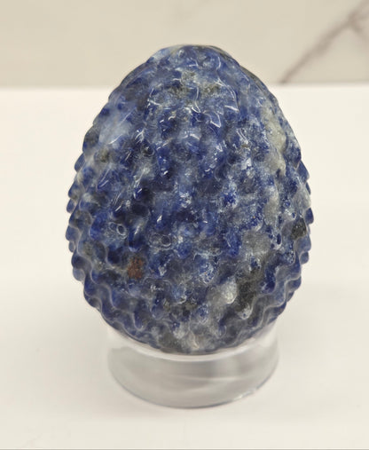 Sodalite dragon egg carving on an acrylic stand against a neutral background