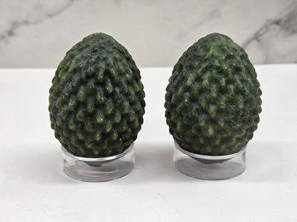 Green Jade dragon egg carvings on acrylic stands against a neutral background
