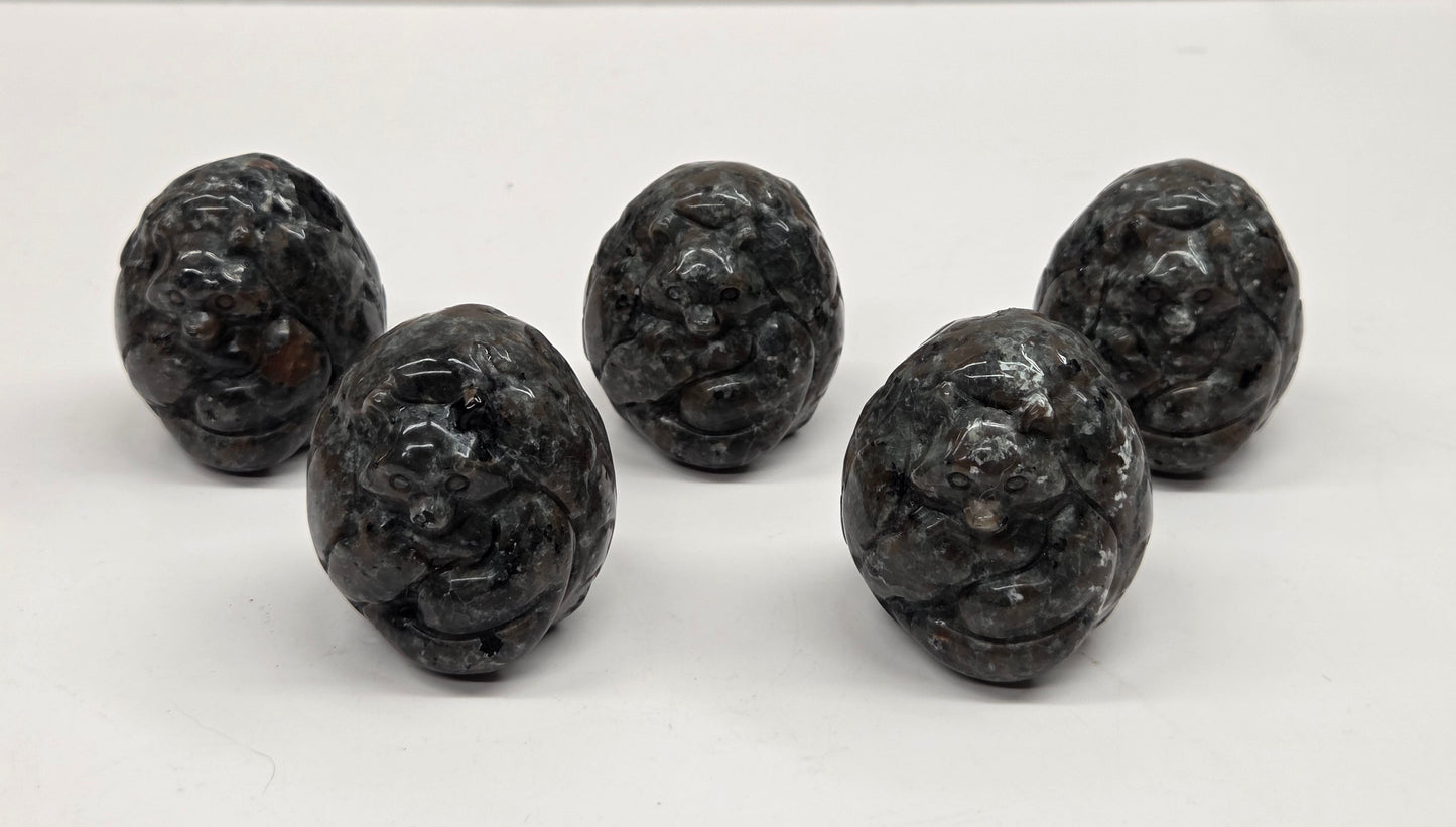 Five yooperlite egg shaped intricate carvings against a neutral background