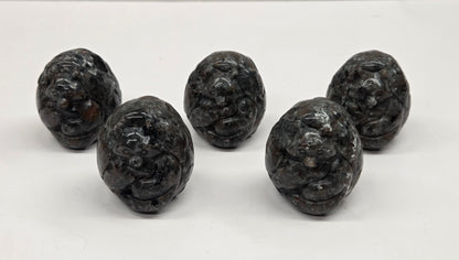 Five yooperlite egg shaped intricate carvings against a neutral background