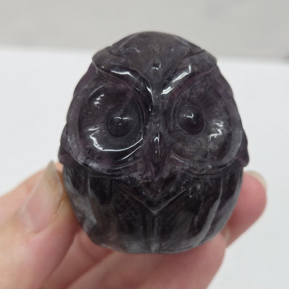 Hand holding a dark stone object with intricate carvings against a white background
