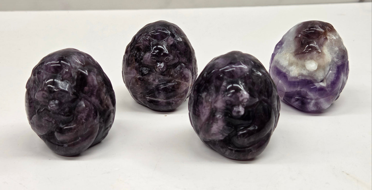 Four amethyst carved stones on a white surface with a marble background