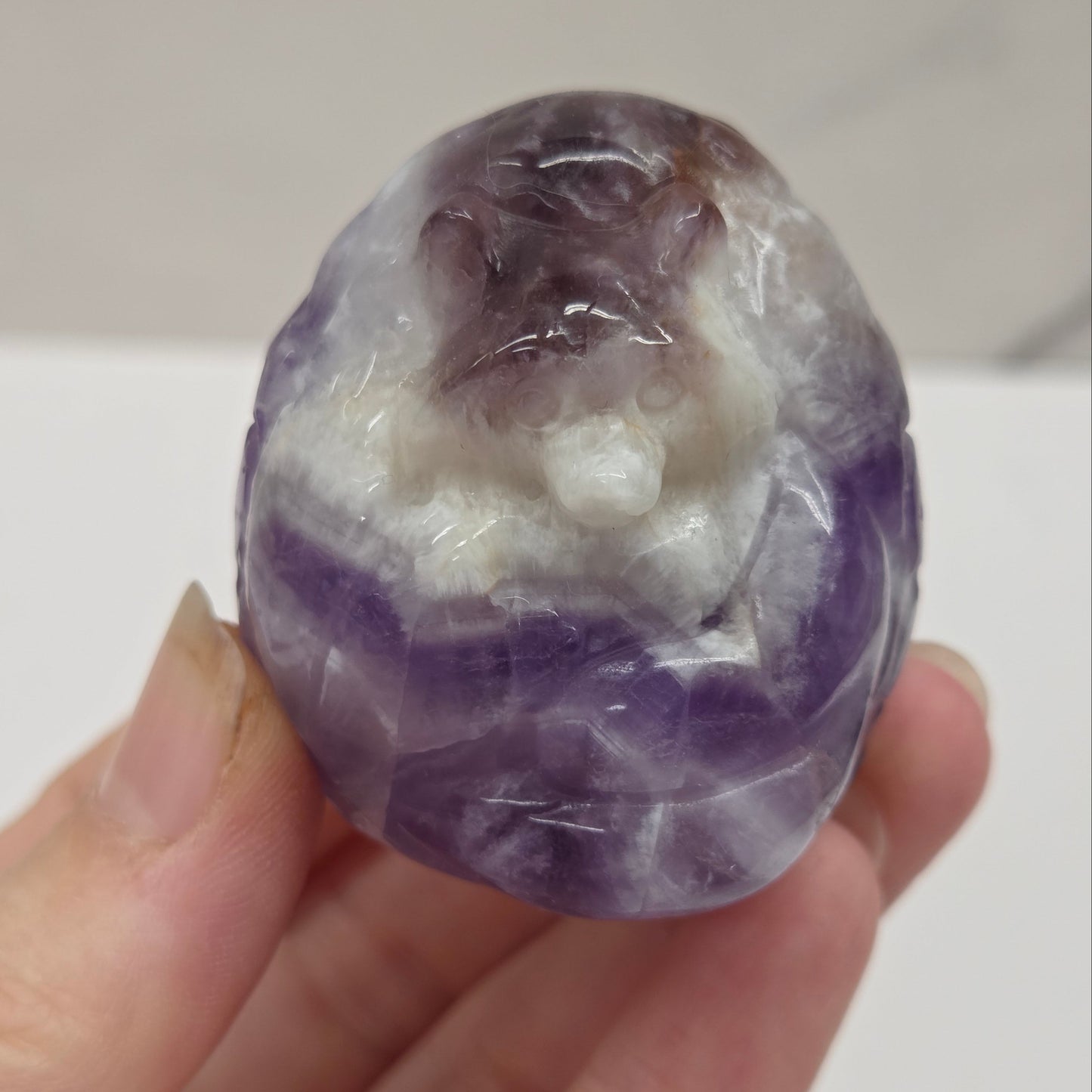 Hand holding a purple and white crystal ball against a plain background