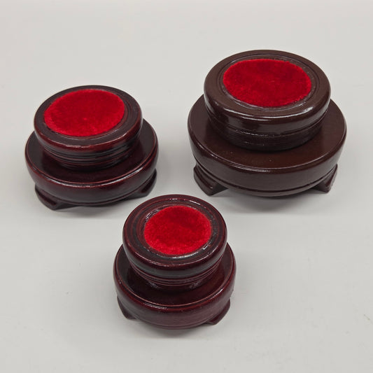 Round wood sphere holders with red velvet on a neutral background