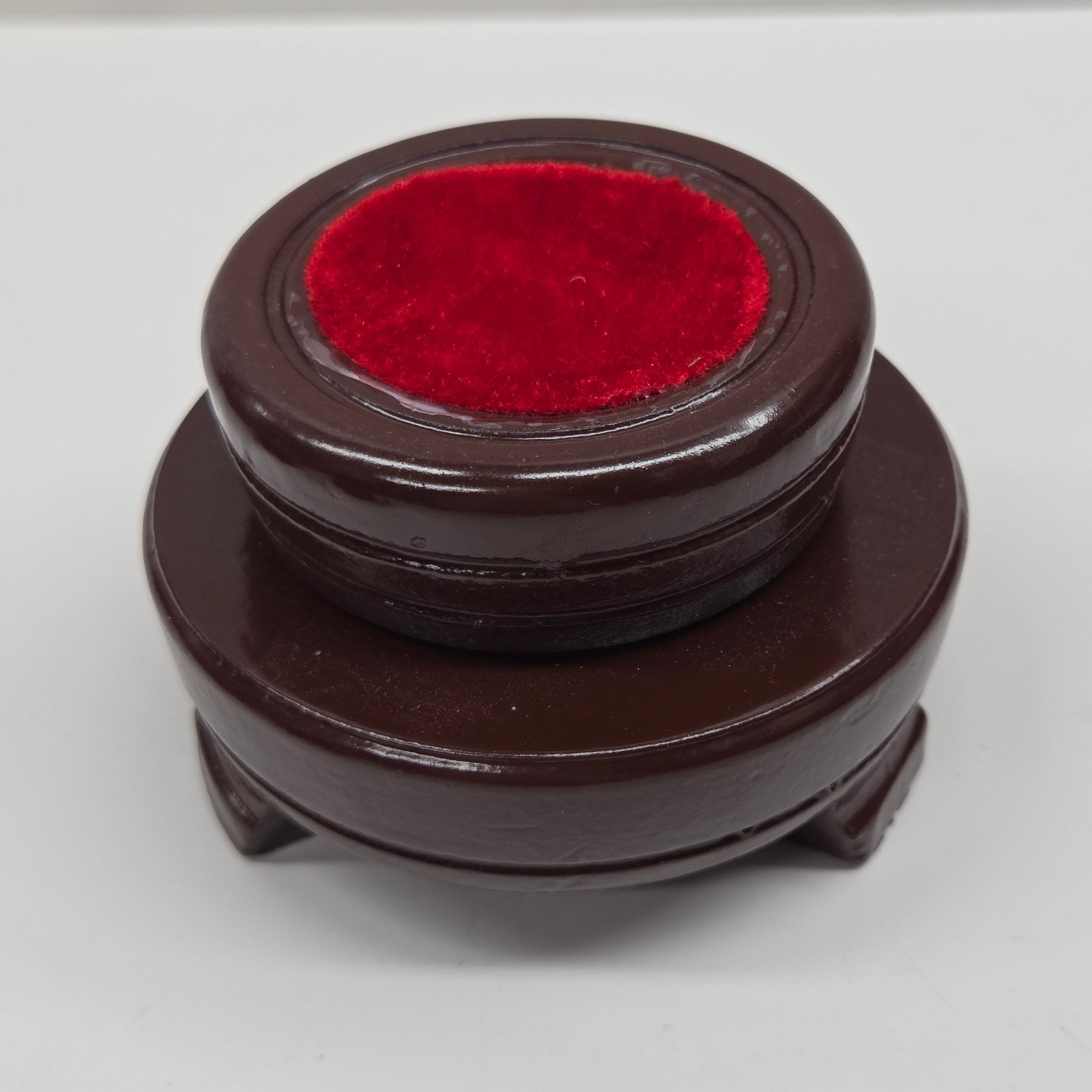 Round wood sphere holder with red velvet on a neutral background