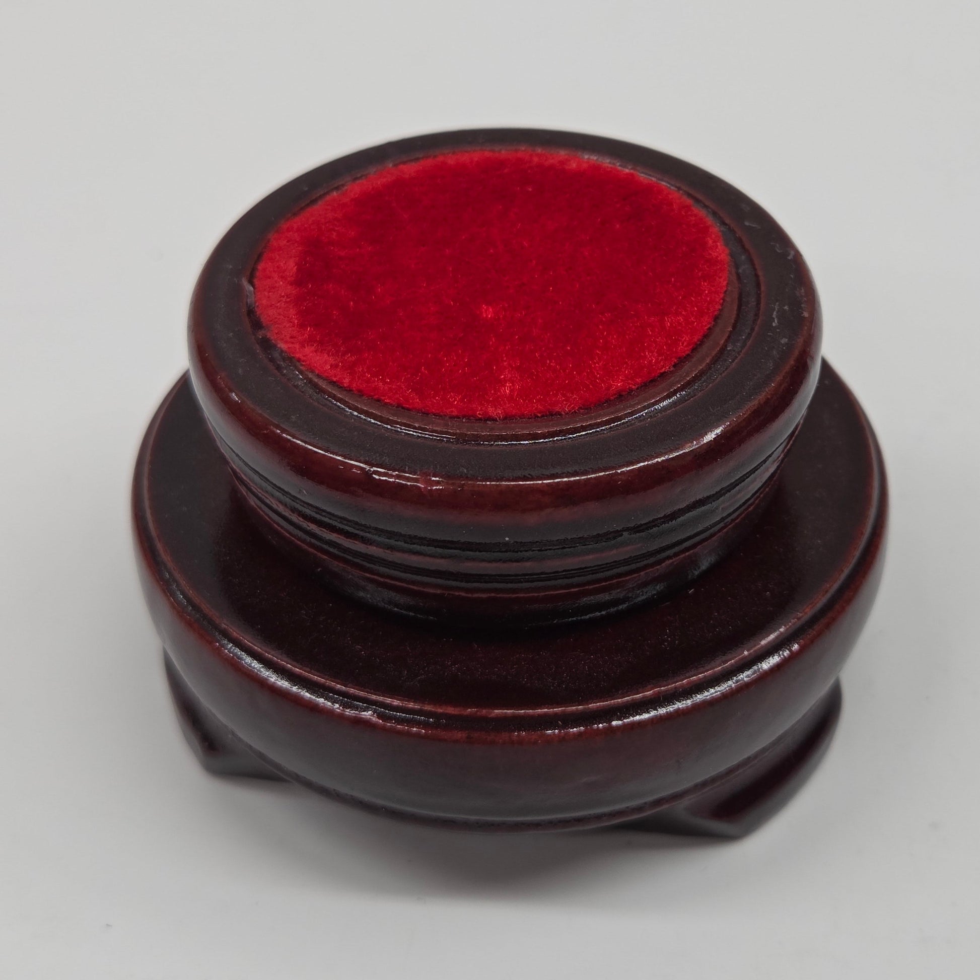 Round wood sphere holder with red velvet on a neutral background