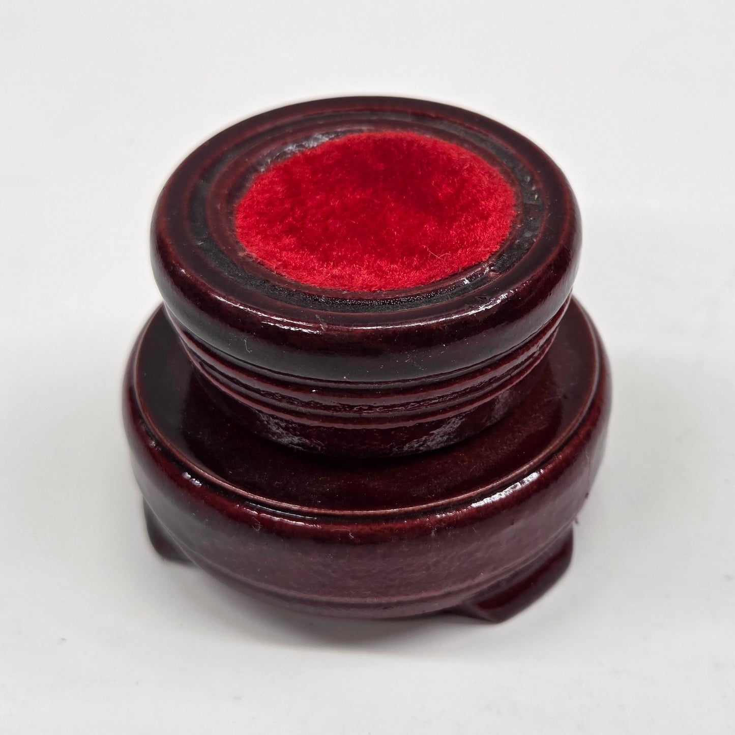 Round wood sphere holder with red velvet on a neutral background