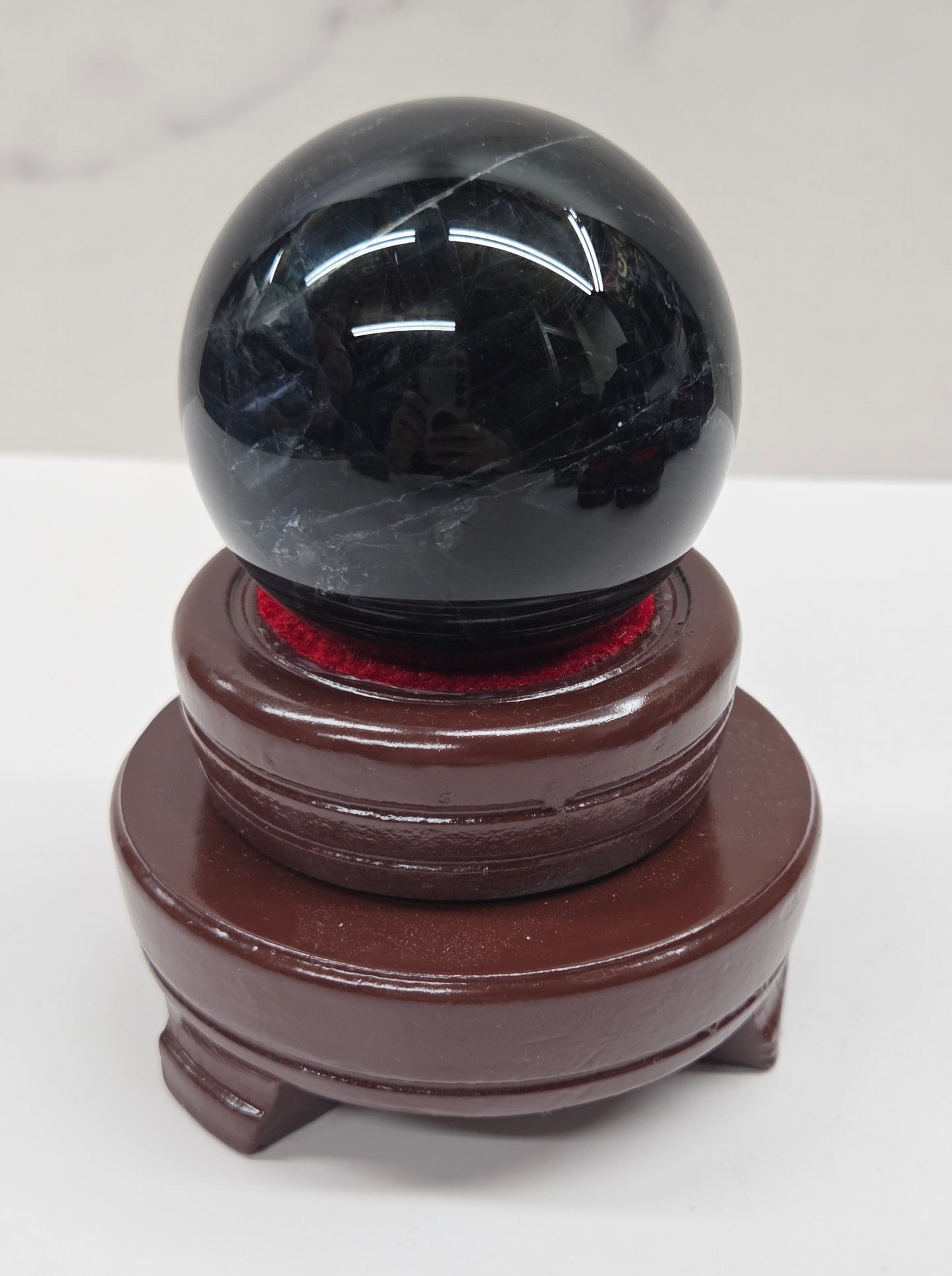 Round wood sphere holder with red velvet holding a sphere on a neutral background