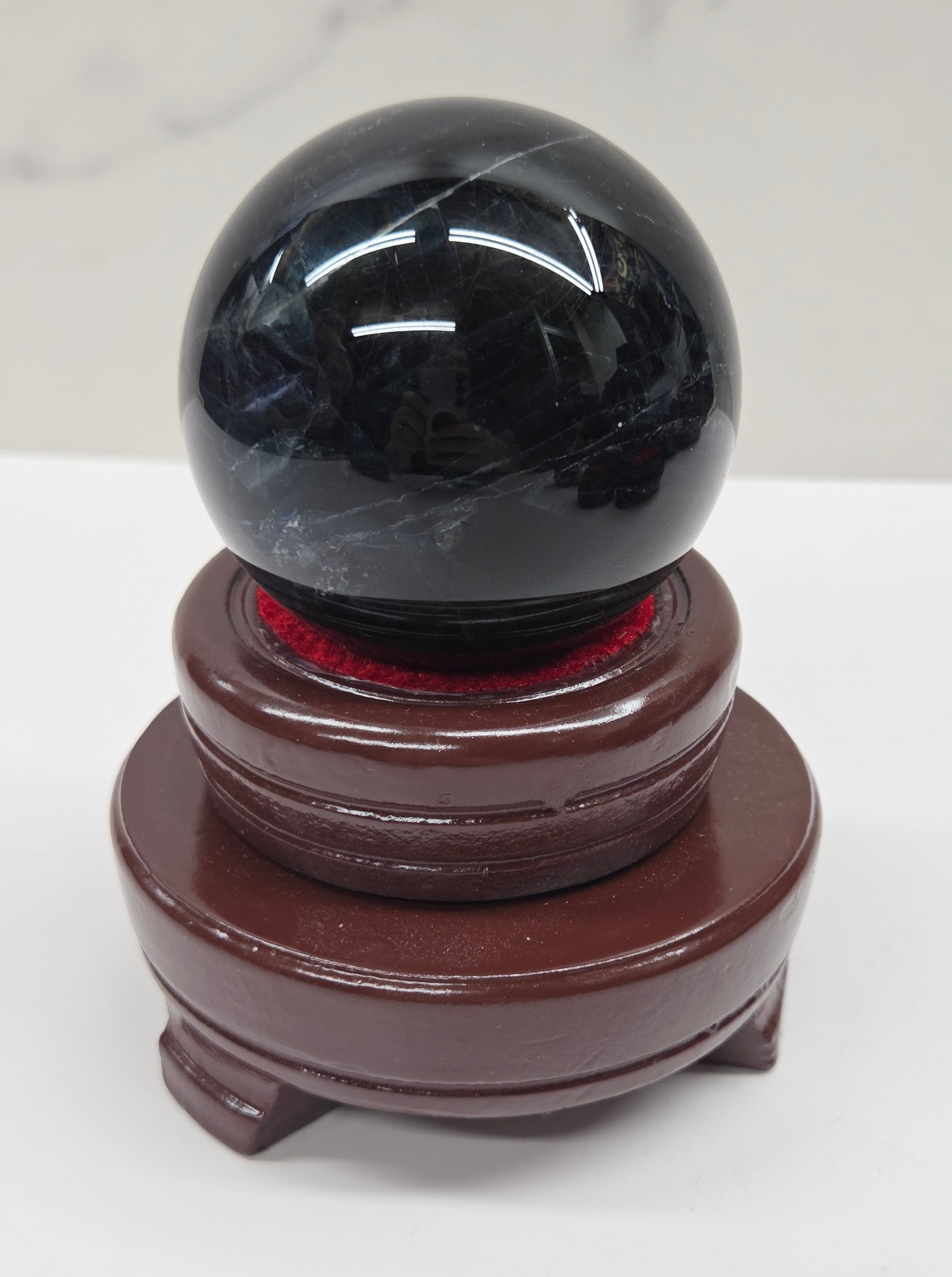 Round wood sphere holder with red velvet holding a sphere on a neutral background