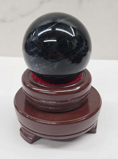 Round wood sphere holder with red velvet holding a sphere on a neutral background