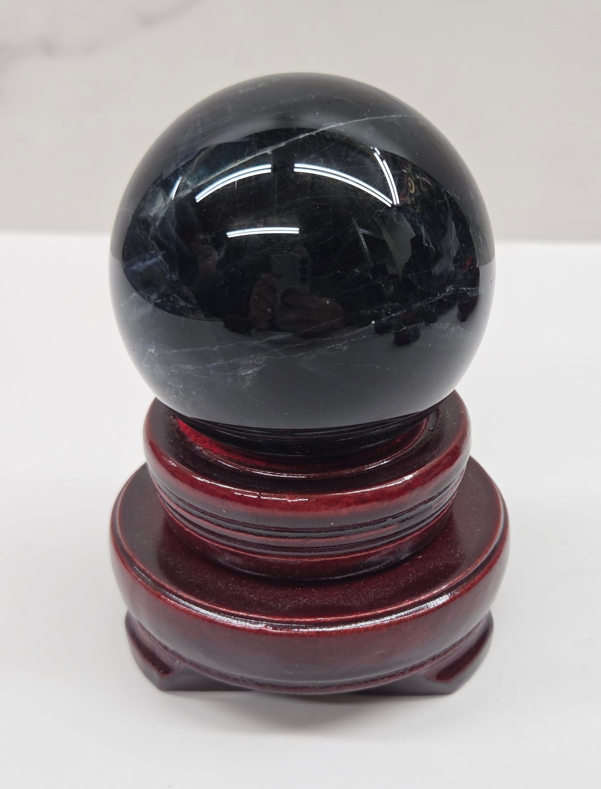 Round wood sphere holder with red velvet holding a sphere on a neutral background