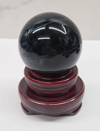 Round wood sphere holder with red velvet holding a sphere on a neutral background