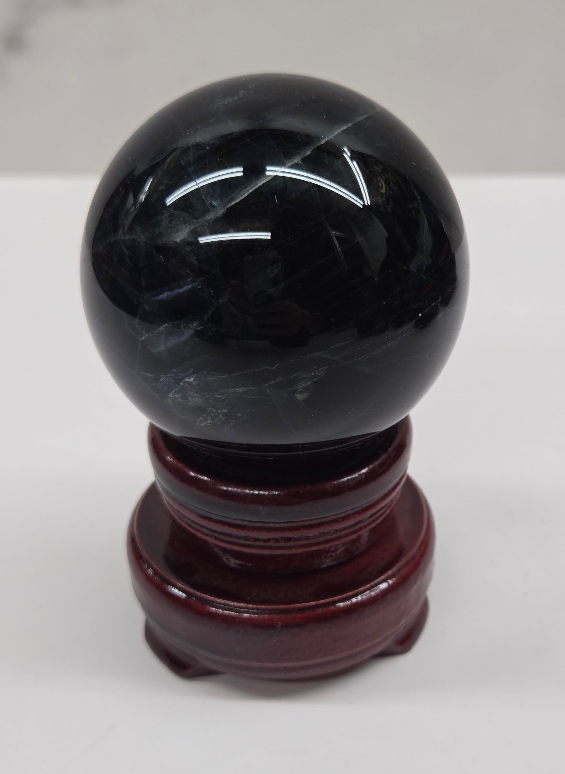 Round wood sphere holder with red velvet holding a sphere on a neutral background