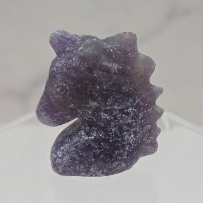 Purple Lepidolite Unicorn head carving on a white background
