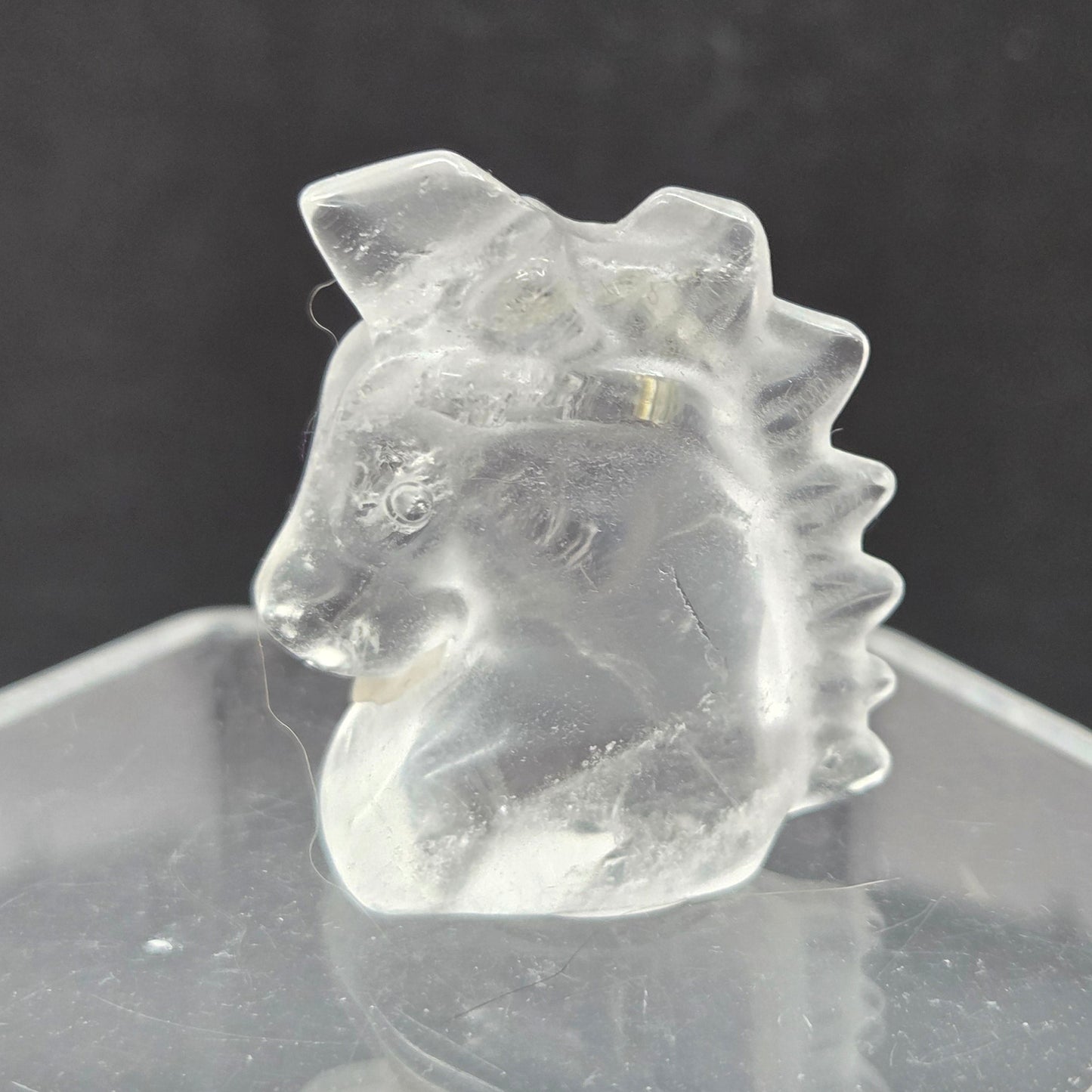 Clear Quartz Unicorn head carving on a dark background