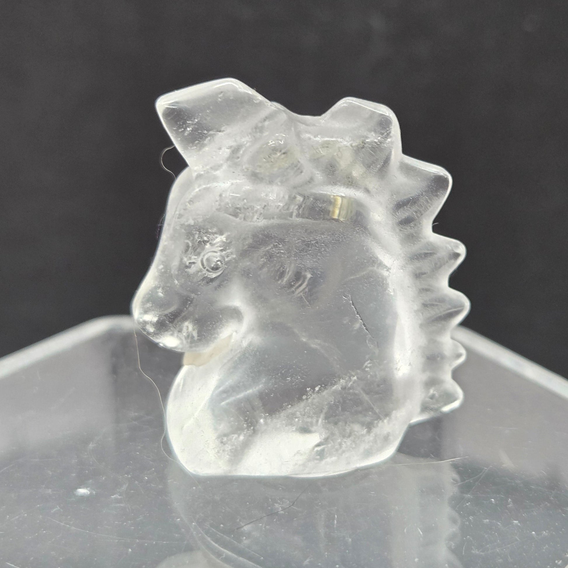 Clear Quartz Unicorn head carving on a dark background