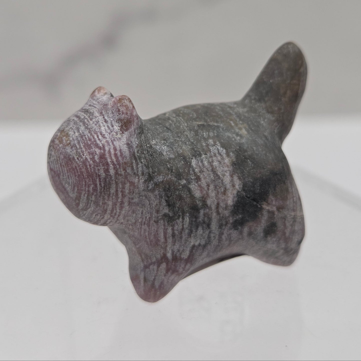 Small stone sculpture of a cat on a white background