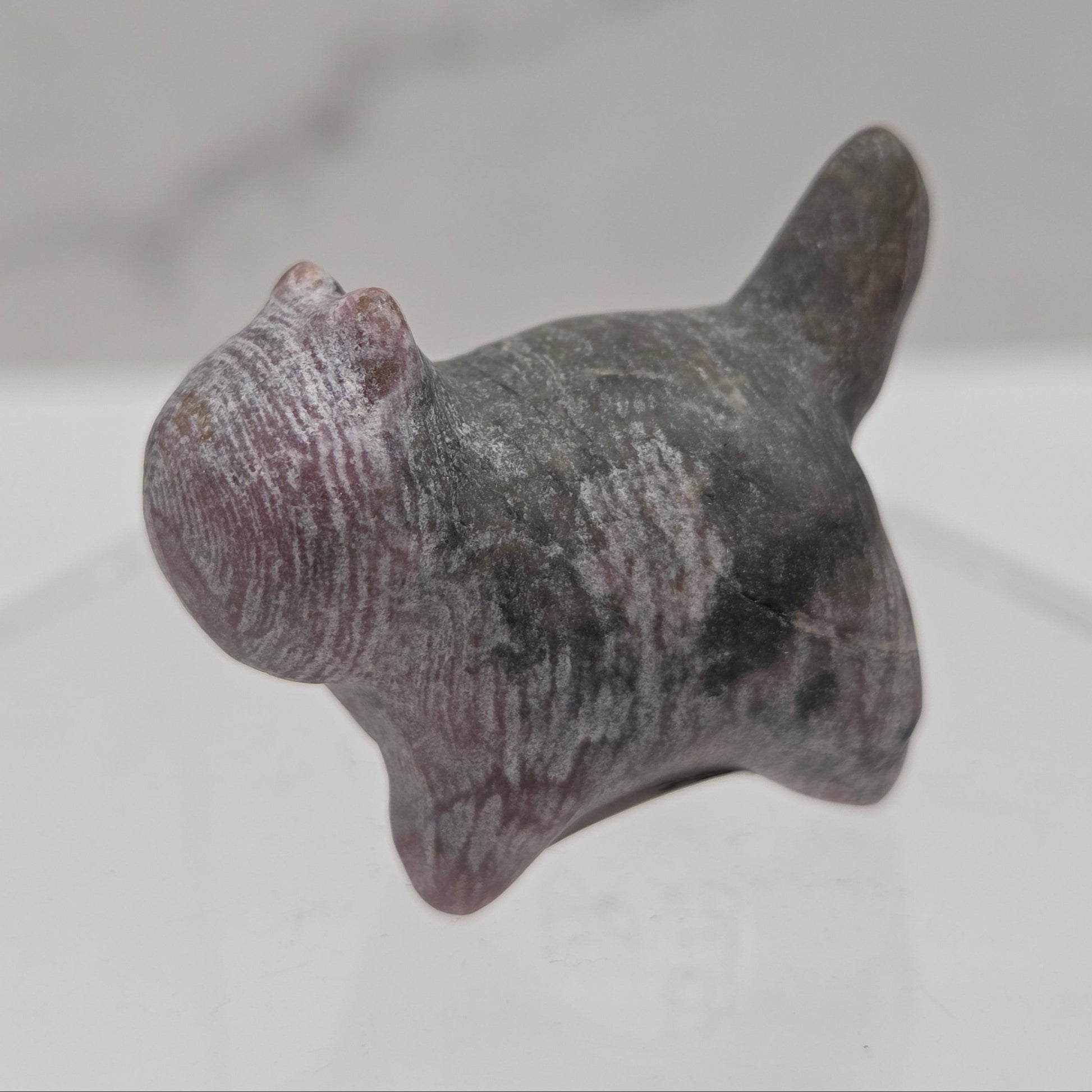 Small stone sculpture of a cat on a white background