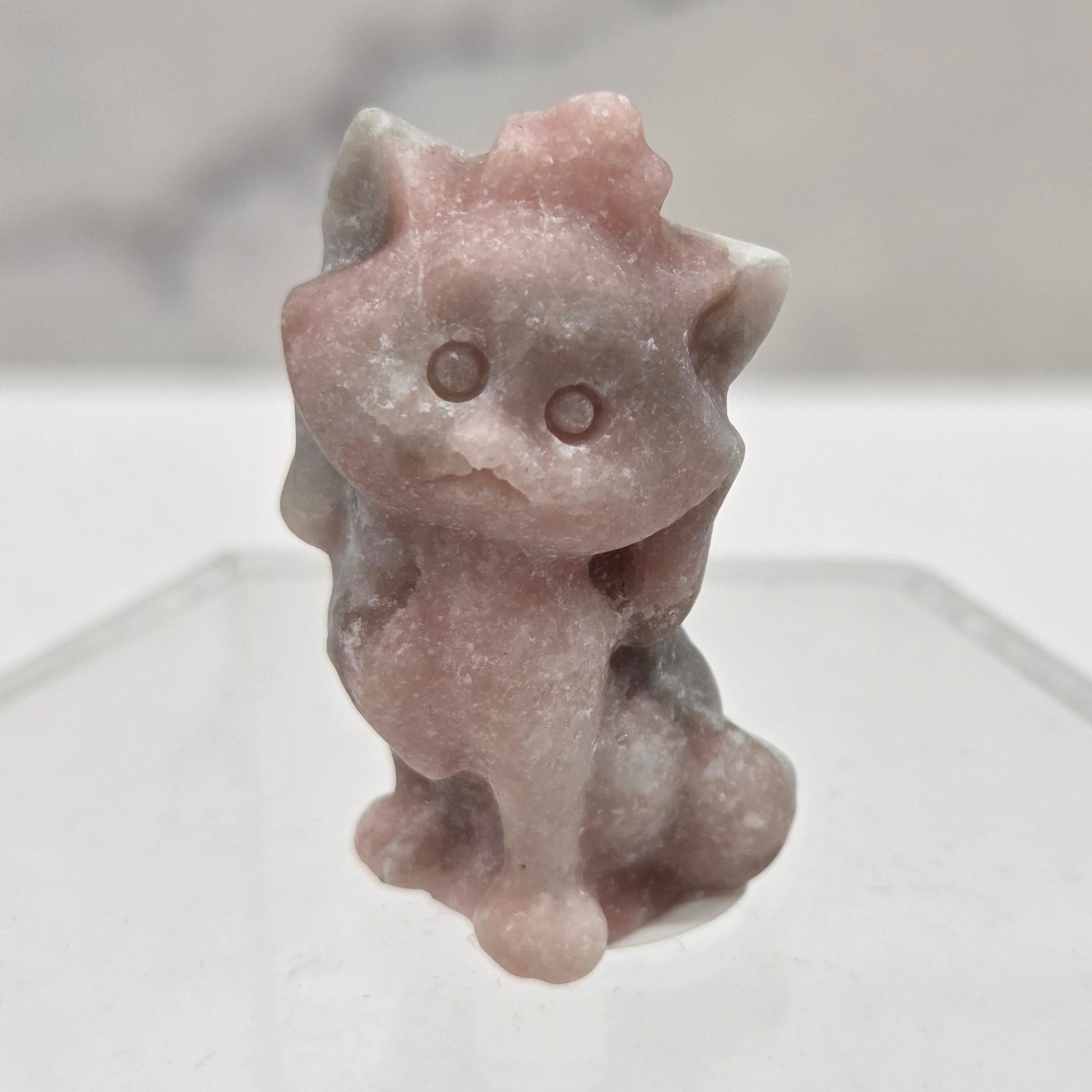 Small stone sculpture resembling a cat on a white background