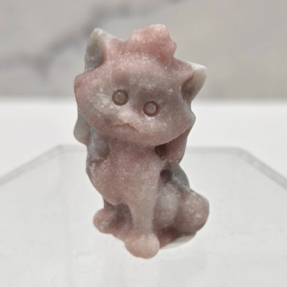 Small stone sculpture resembling a cat on a white background