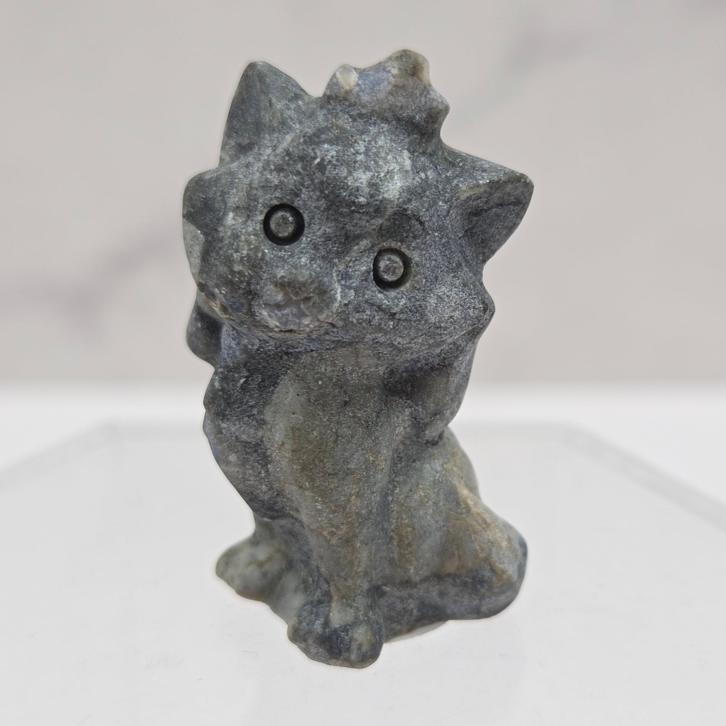 Small stone sculpture resembling a cat on a white background