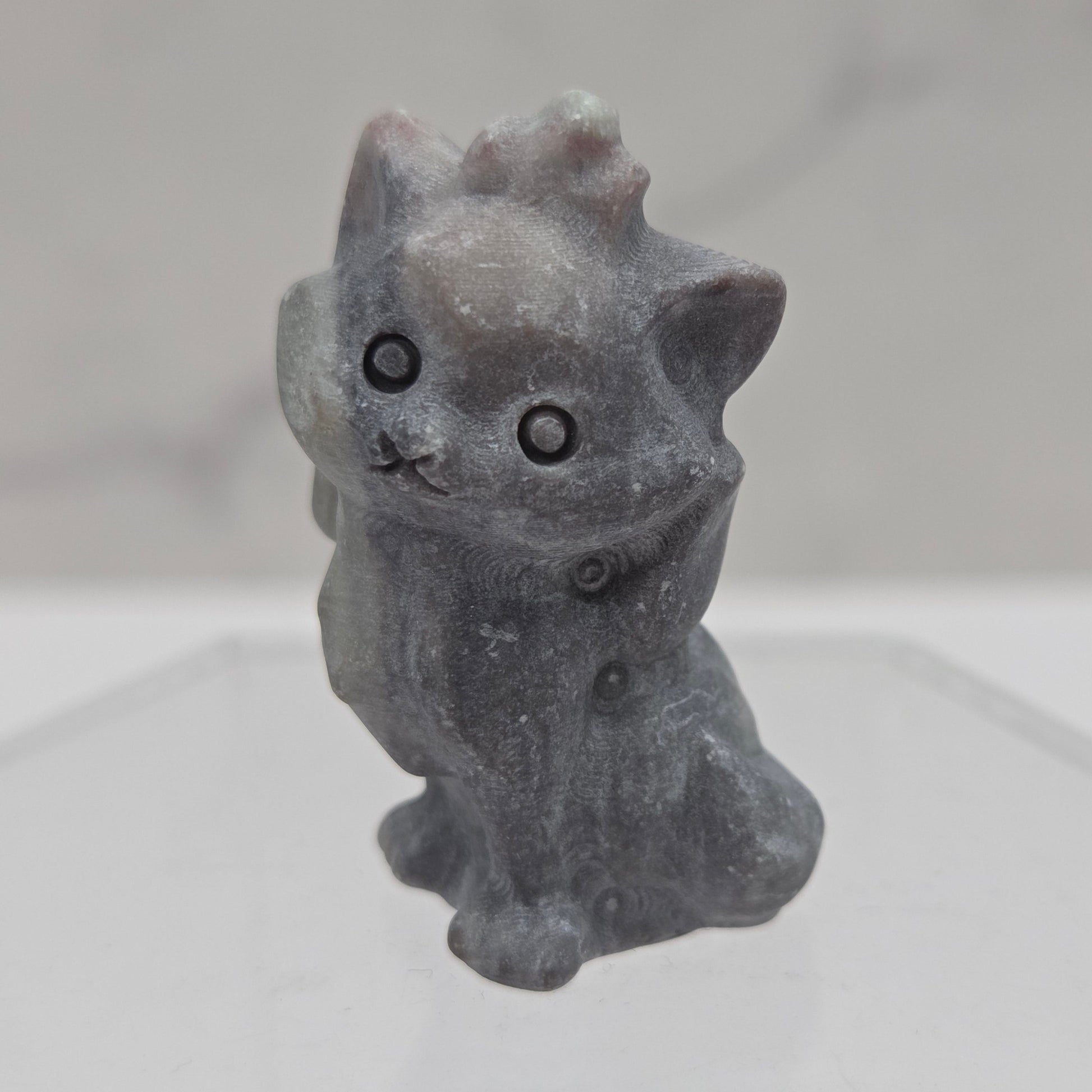 Small stone sculpture resembling a cat on a white background
