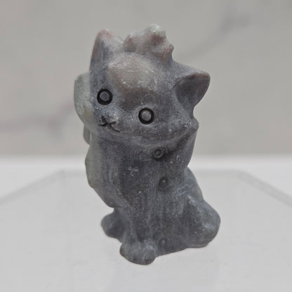 Small stone sculpture resembling a cat on a white background