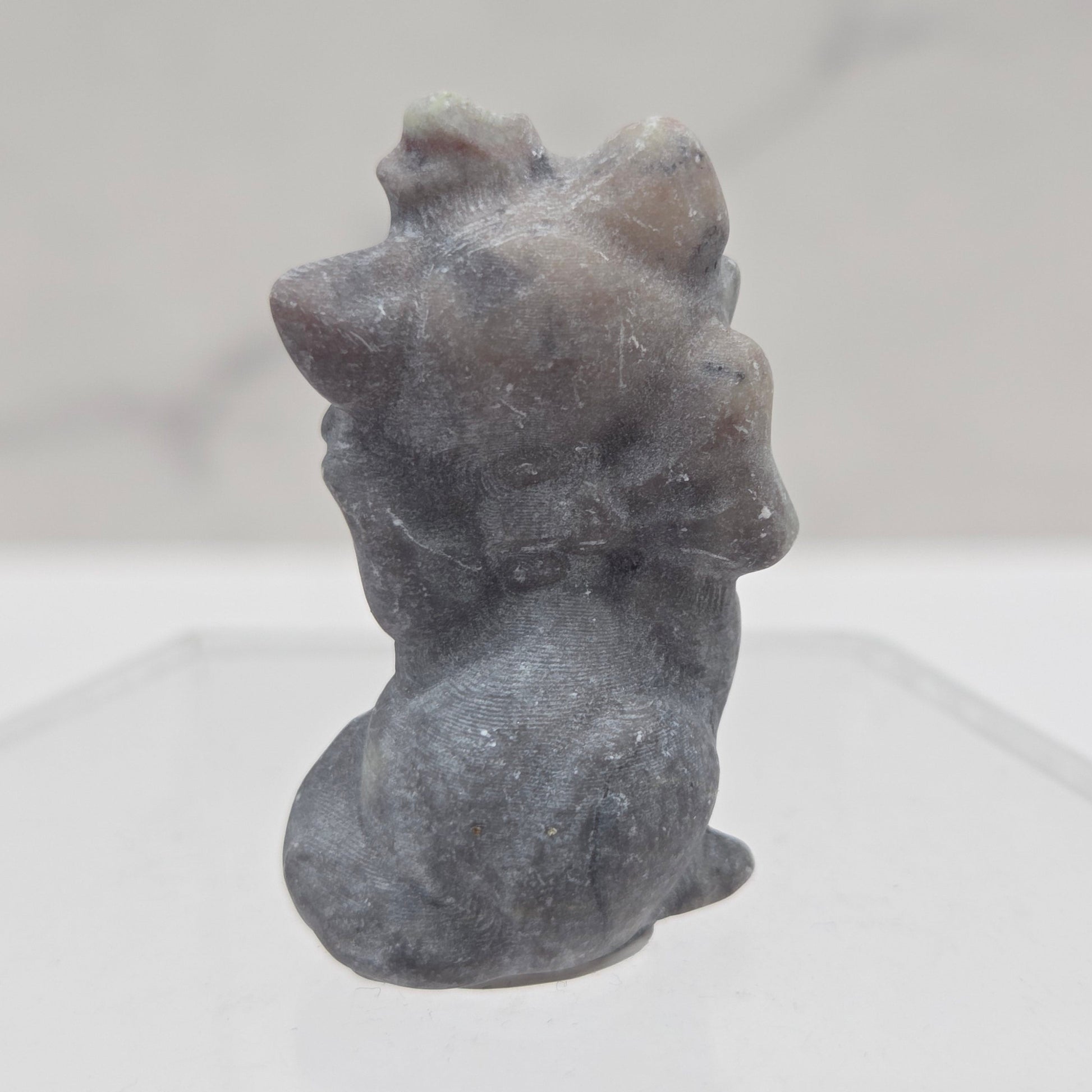 Small stone sculpture resembling a cat on a white background