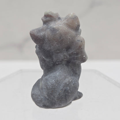 Small stone sculpture resembling a cat on a white background