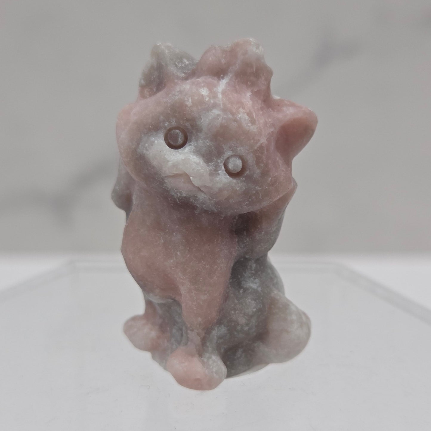 Small stone sculpture resembling a cat on a white background