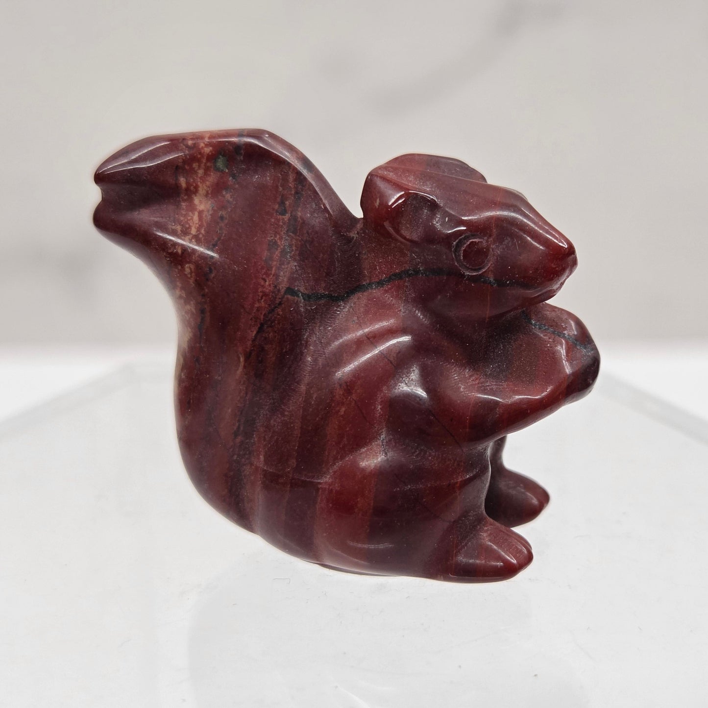 Carved red stone squirrel figure on a white background