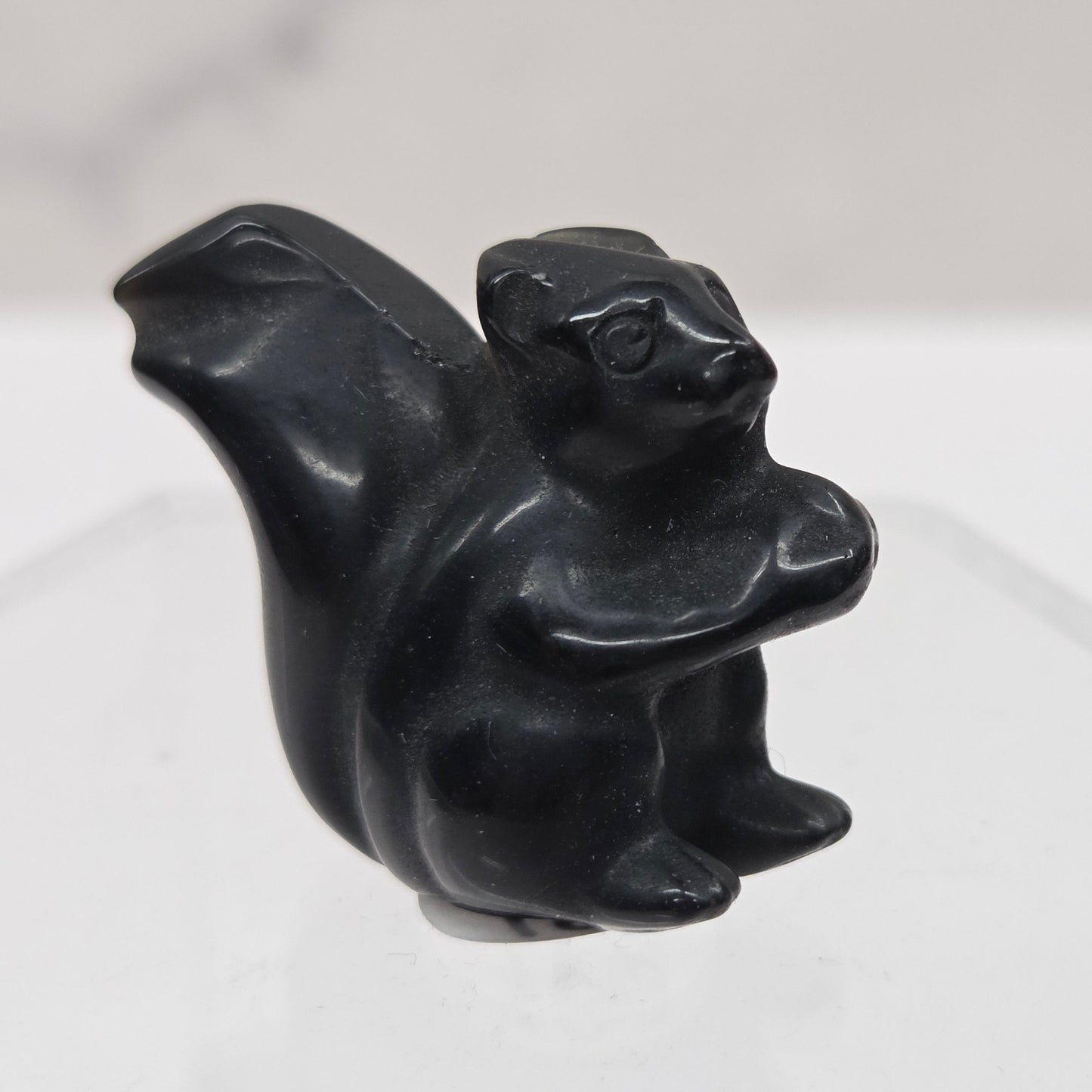 Black stone carving of a stylized animal on a white background