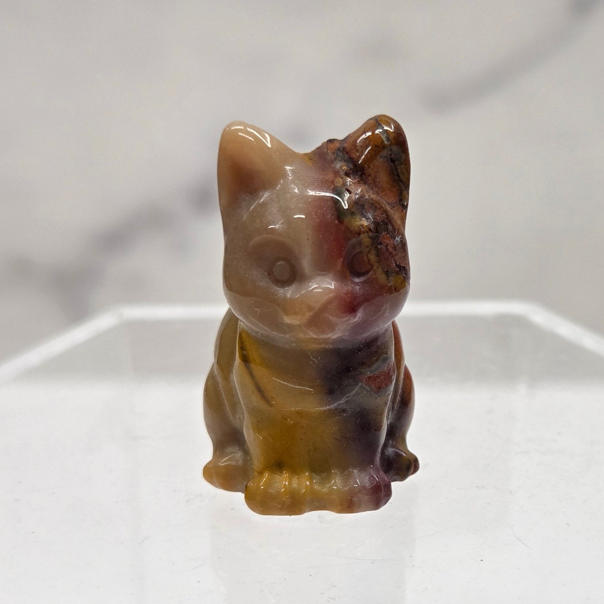 Mookaite cat carving in red, yellow, and brown on a white background