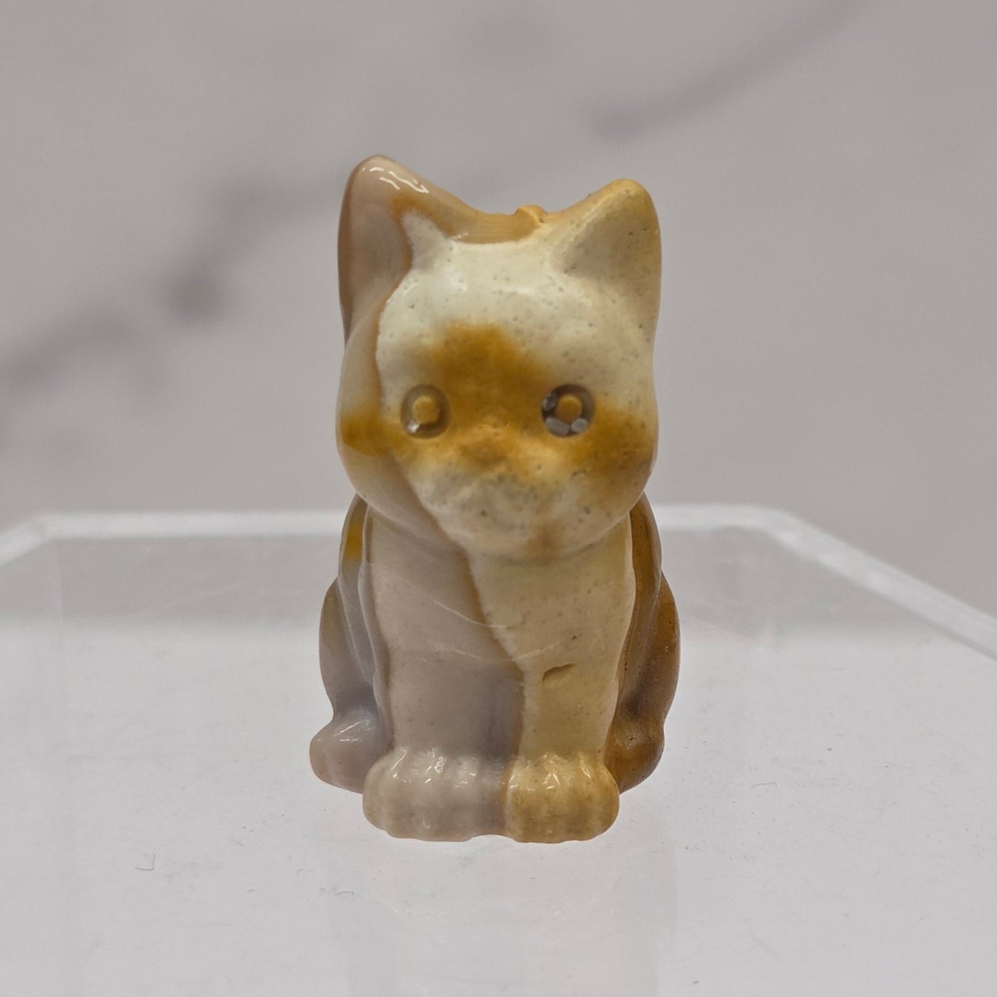Mookaite cat carving in red, yellow, and brown on a white background