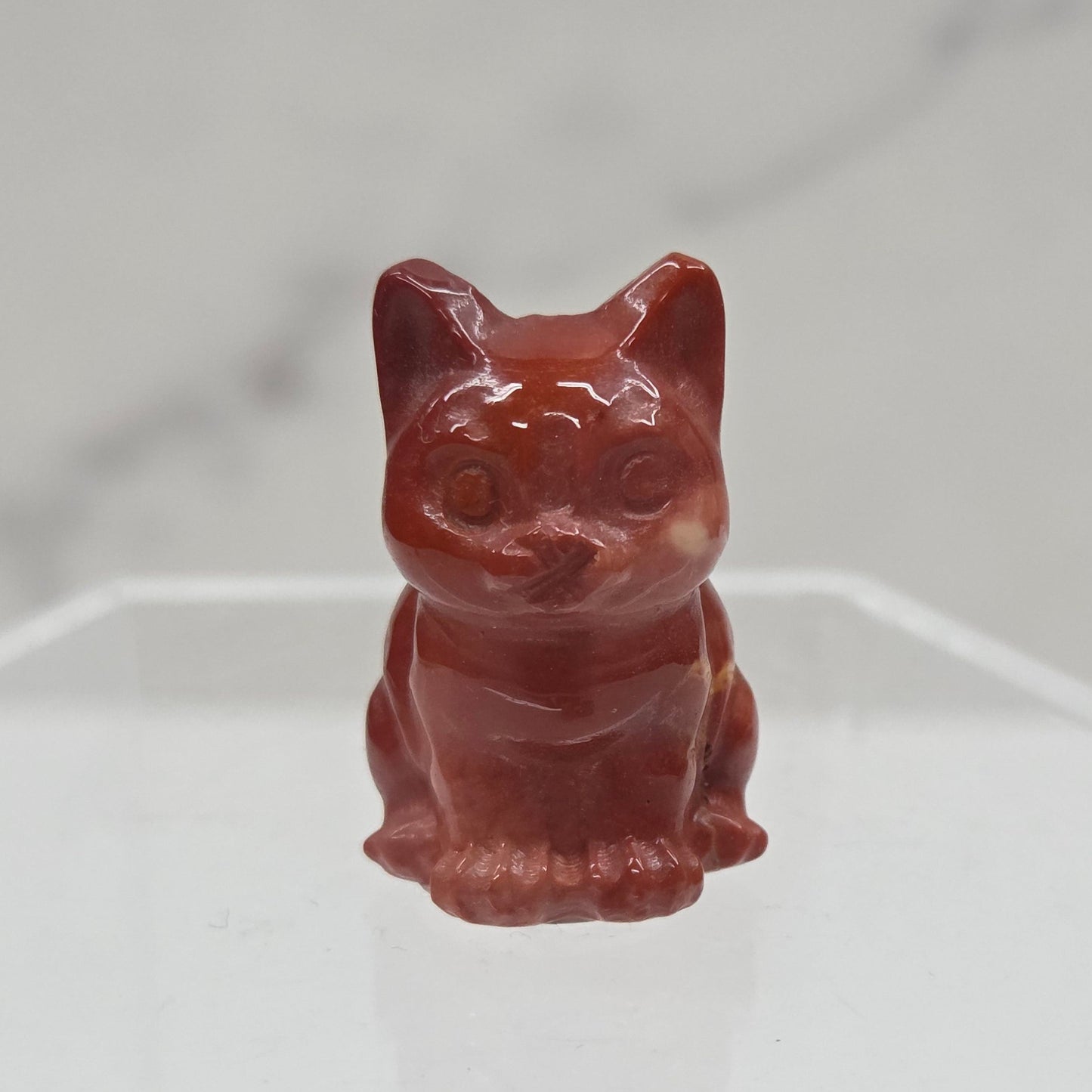 Mookaite cat carving in red, yellow, and brown on a white background