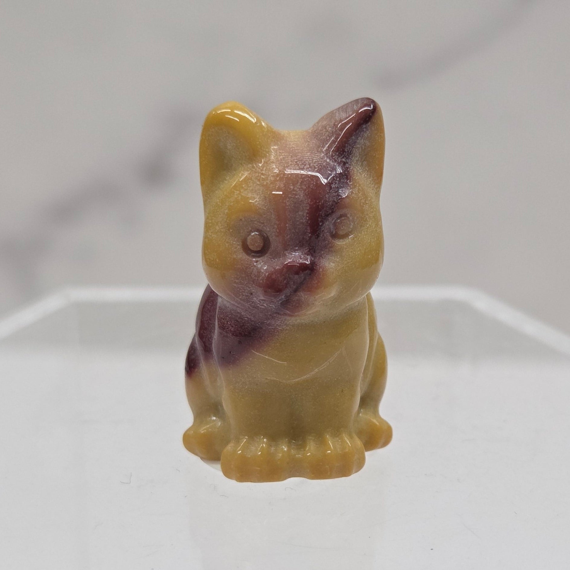 Mookaite cat carving in red, yellow, and brown on a white background
