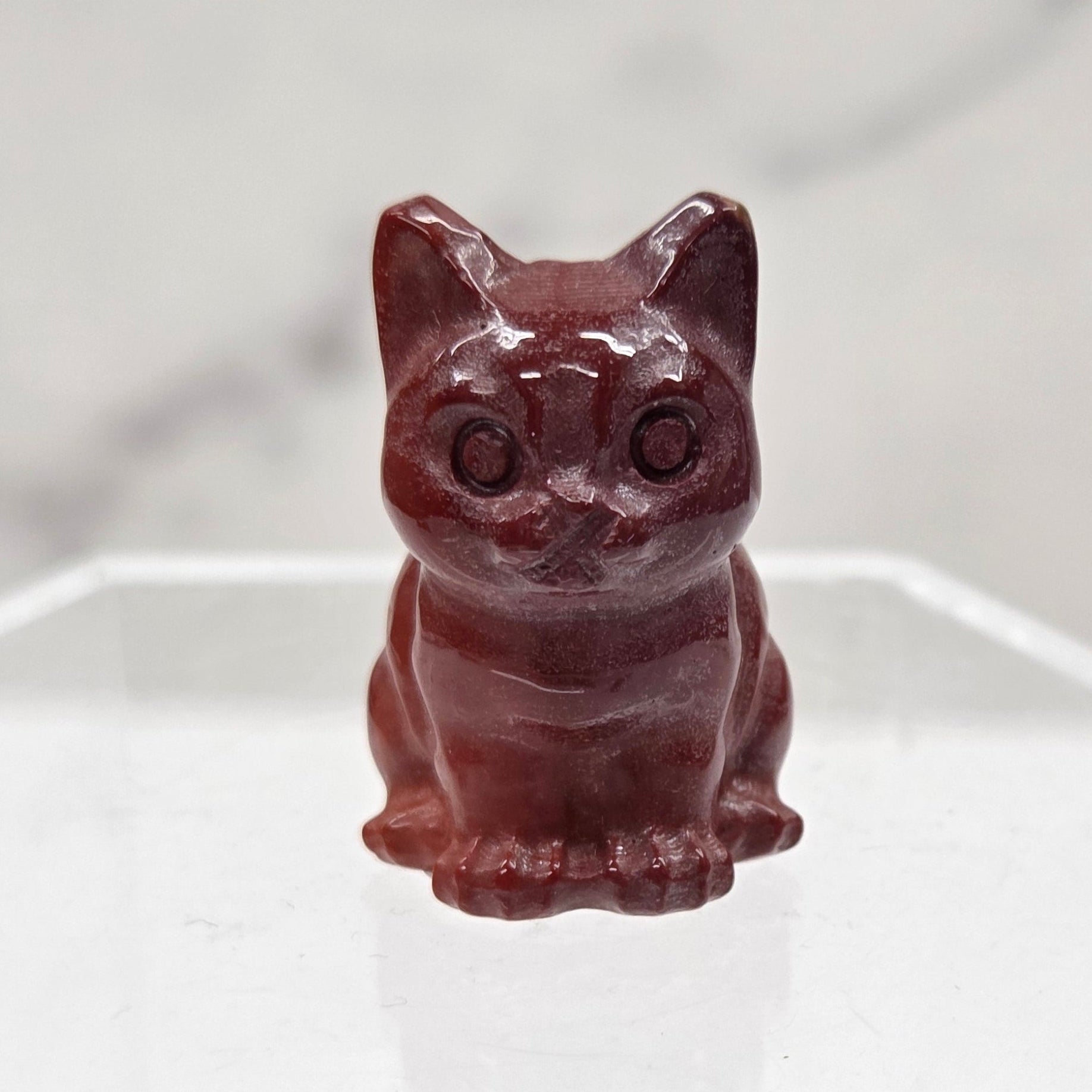 Mookaite cat carving in red, yellow, and brown on a white background