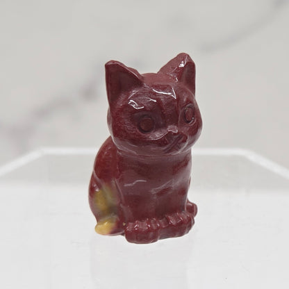 Mookaite cat carving in red, yellow, and brown on a white background