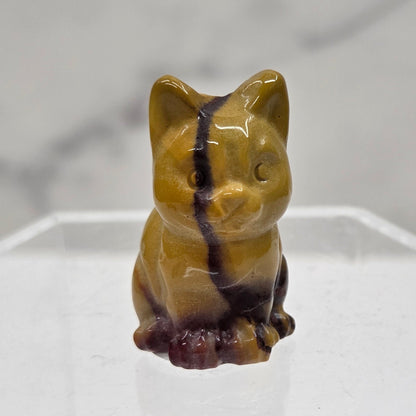 Mookaite cat carving in red, yellow, and brown on a white background