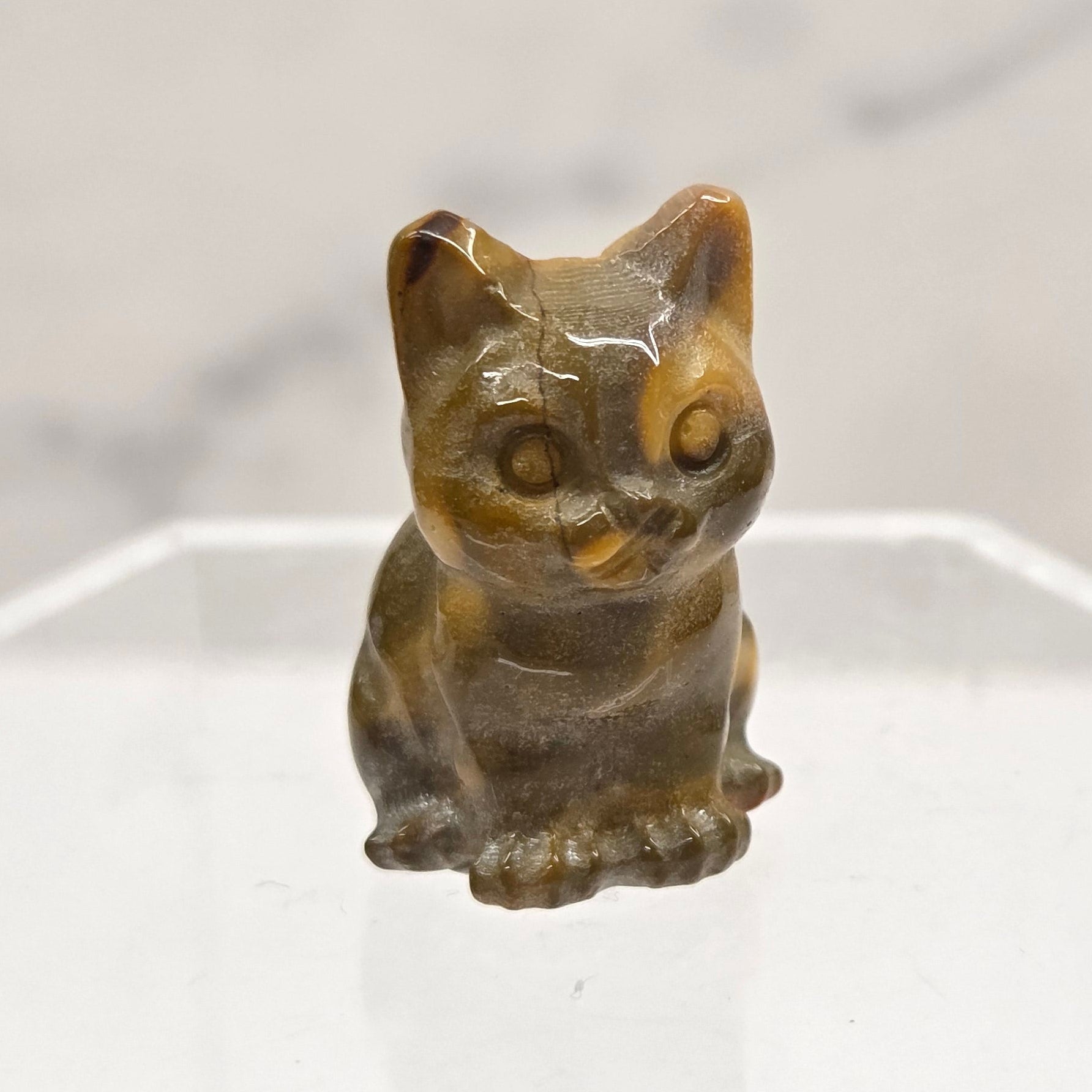 Mookaite cat carving in red, yellow, and brown on a white background