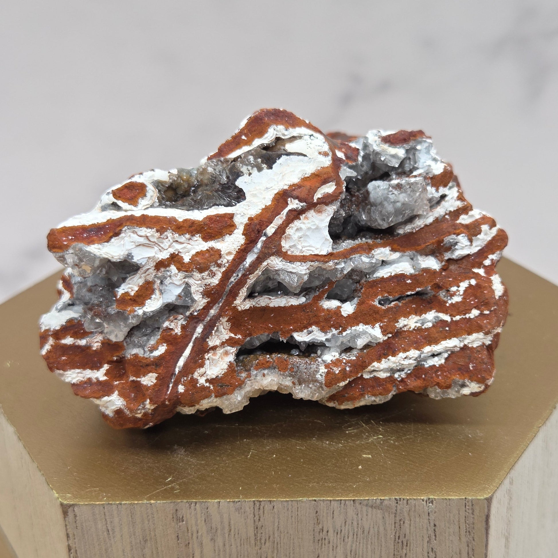 Mineral sample with a white powdery coating on a wooden block