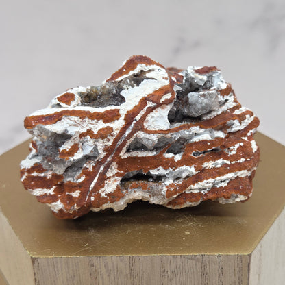 Mineral sample with a white powdery coating on a wooden block